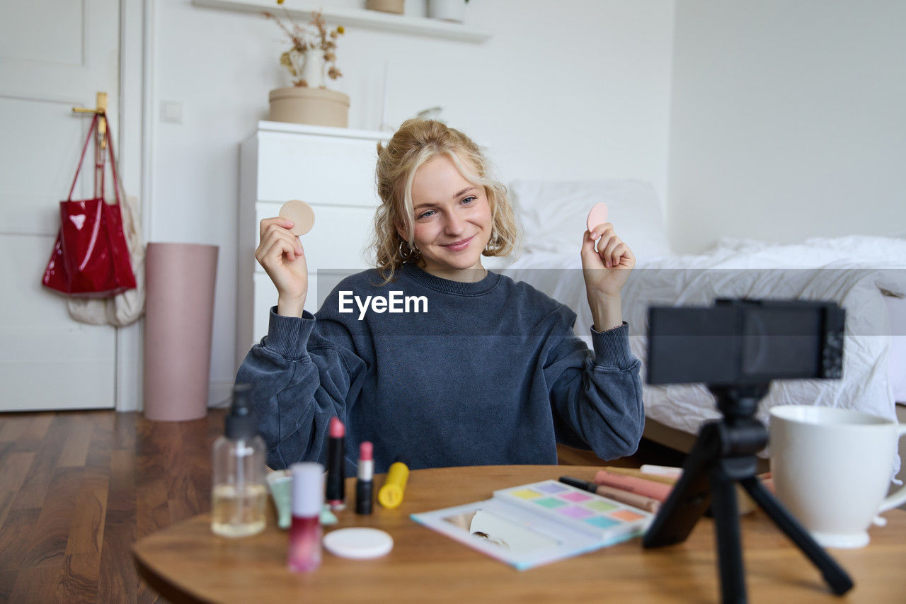 portrait of young woman using mobile phone while sitting on table