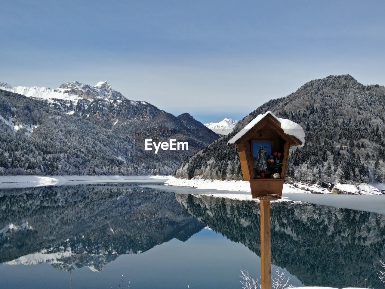 Religious structure against snowcapped mountains reflecting on lake