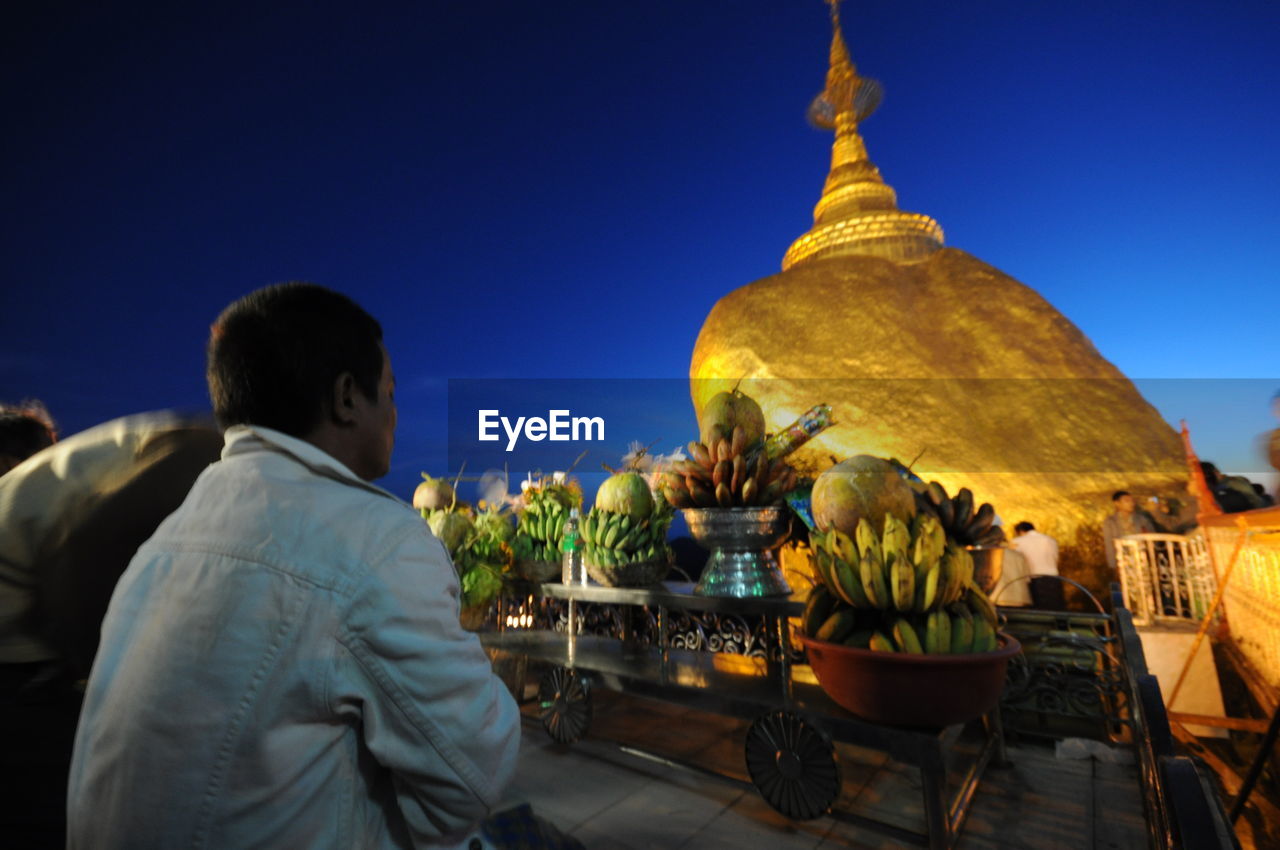 Rear view of man looking at stupa at night