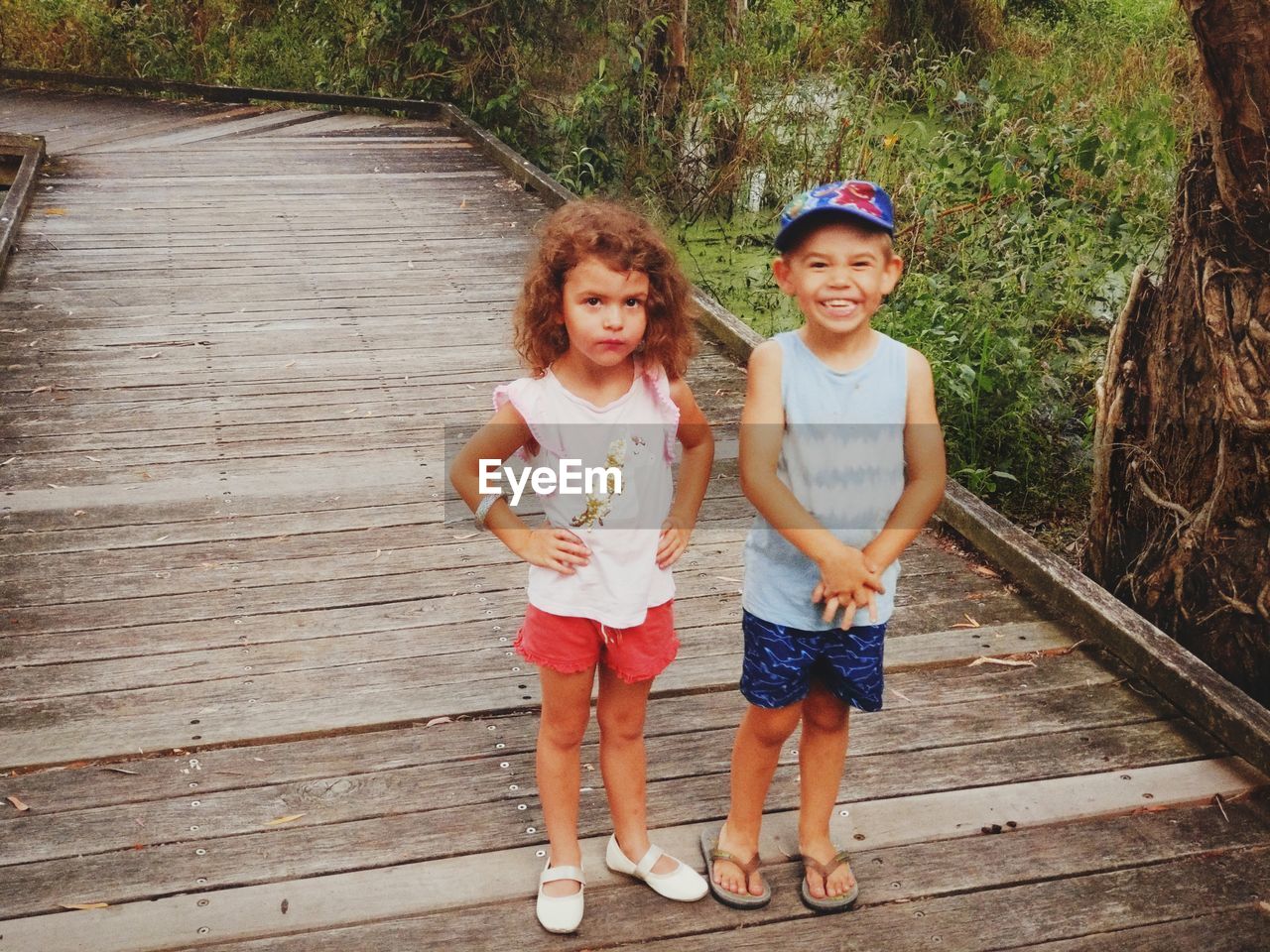 Portrait of smiling boy and girl standing against trees