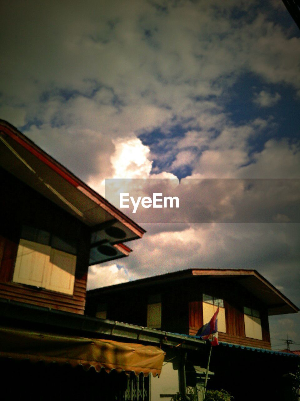 LOW ANGLE VIEW OF HOUSES AGAINST CLOUDY SKY