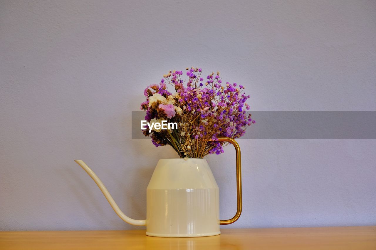 Close-up of flower vase on table against wall