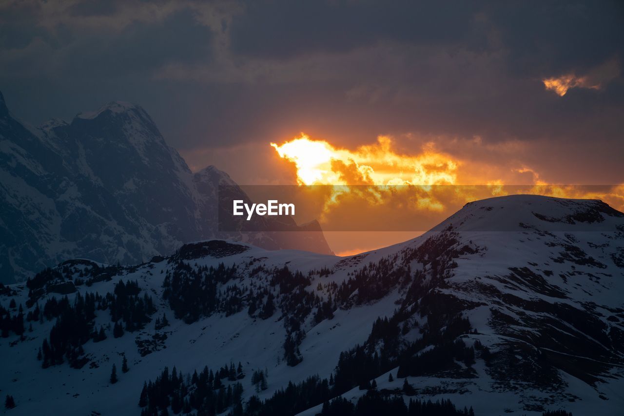 SCENIC VIEW OF SNOW MOUNTAINS AGAINST SKY DURING SUNSET