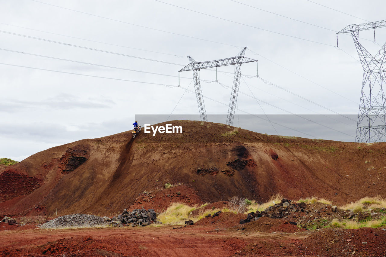 Low angle view of electricity pylons on mountain against sky