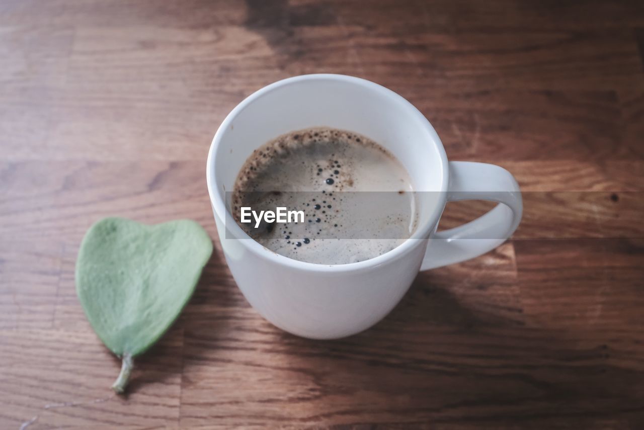 HIGH ANGLE VIEW OF COFFEE CUP ON WOODEN TABLE
