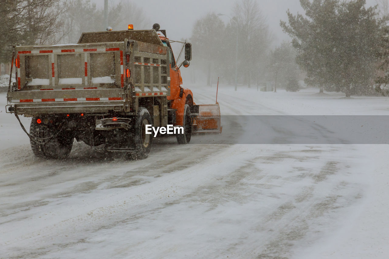 VEHICLES ON ROAD AMIDST SNOW FIELD