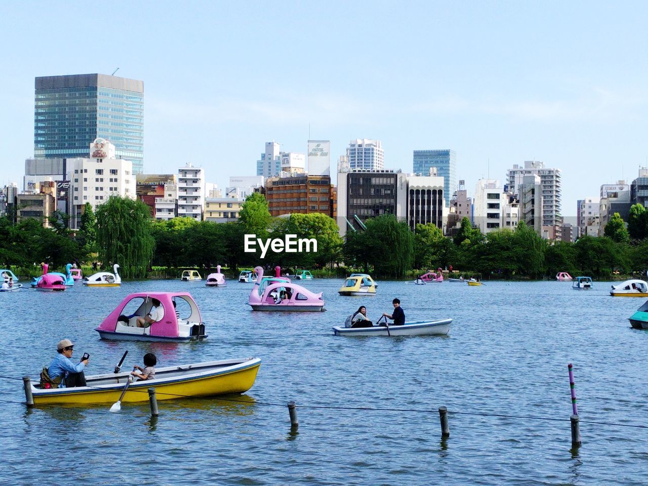 PEOPLE ON BOATS IN RIVER AGAINST CITYSCAPE