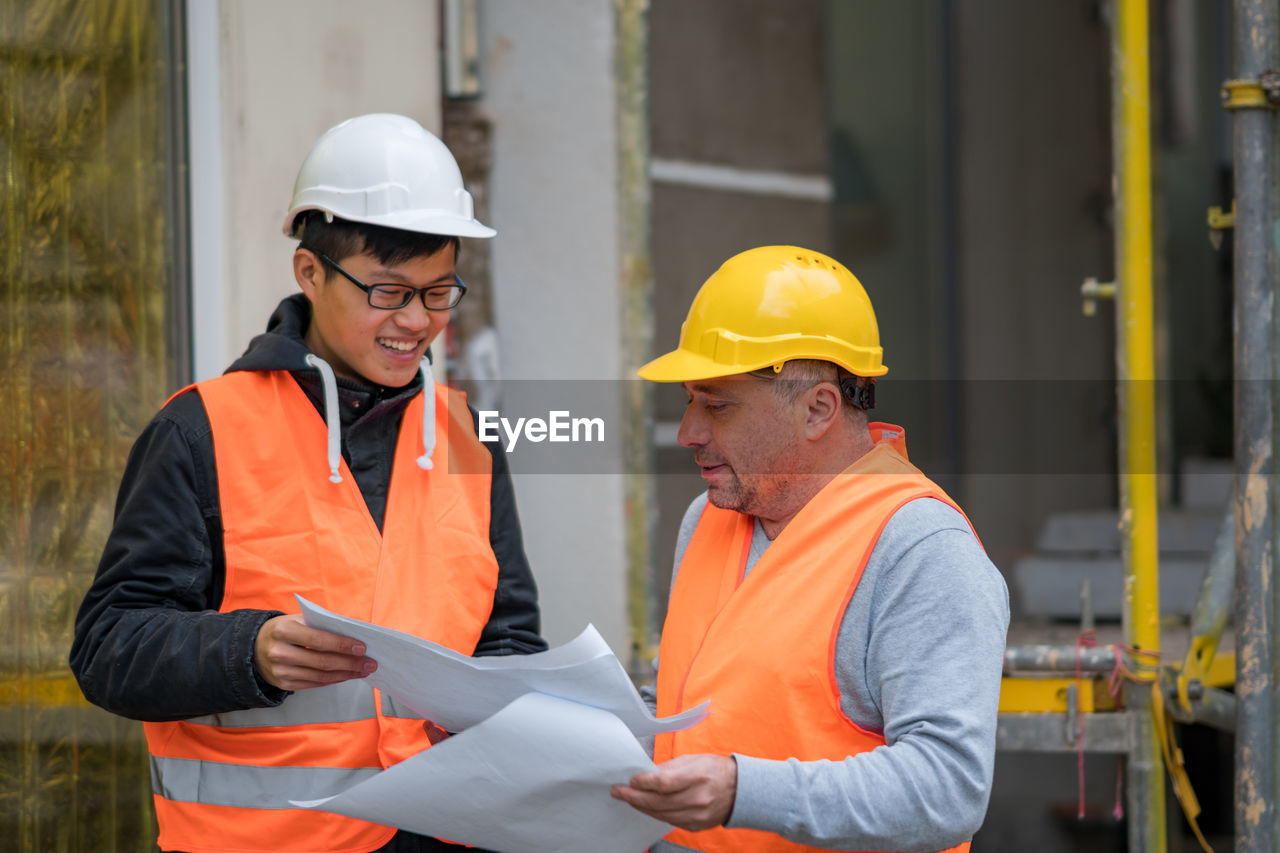 Engineers discussing while standing at construction site