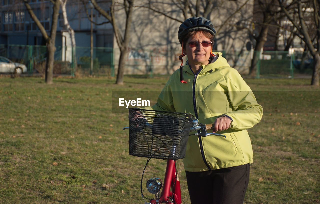 Portrait of woman with bicycle standing on field