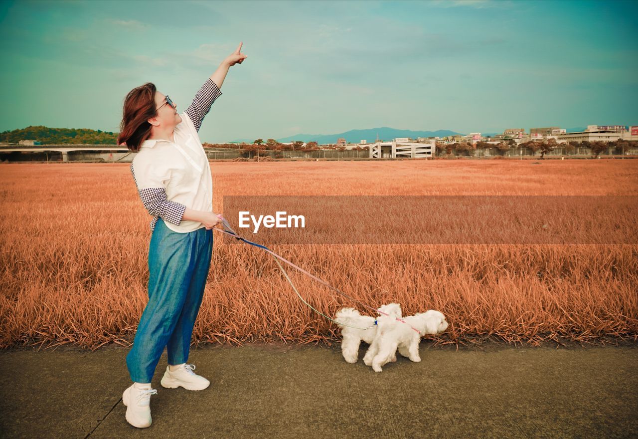 Woman pointing while standing with dogs on road