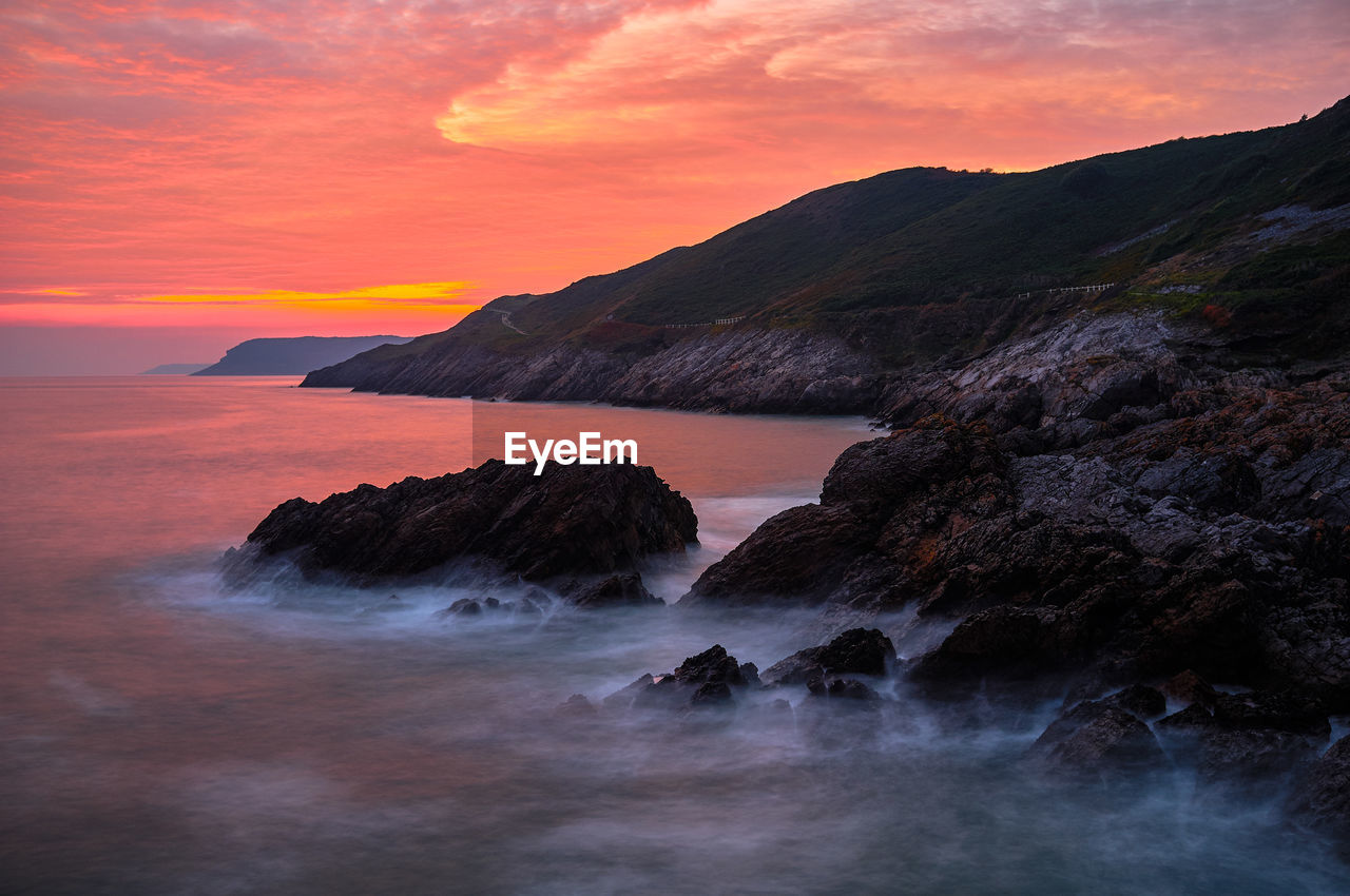 Scenic view of sea against dramatic sky during sunset