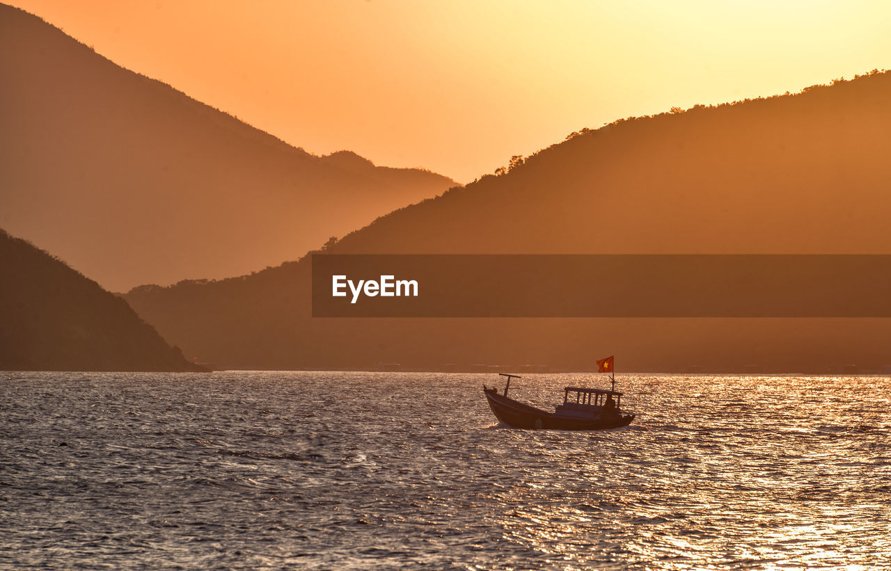 Small wooden fishing boat towards sunset at whale island, vietnam