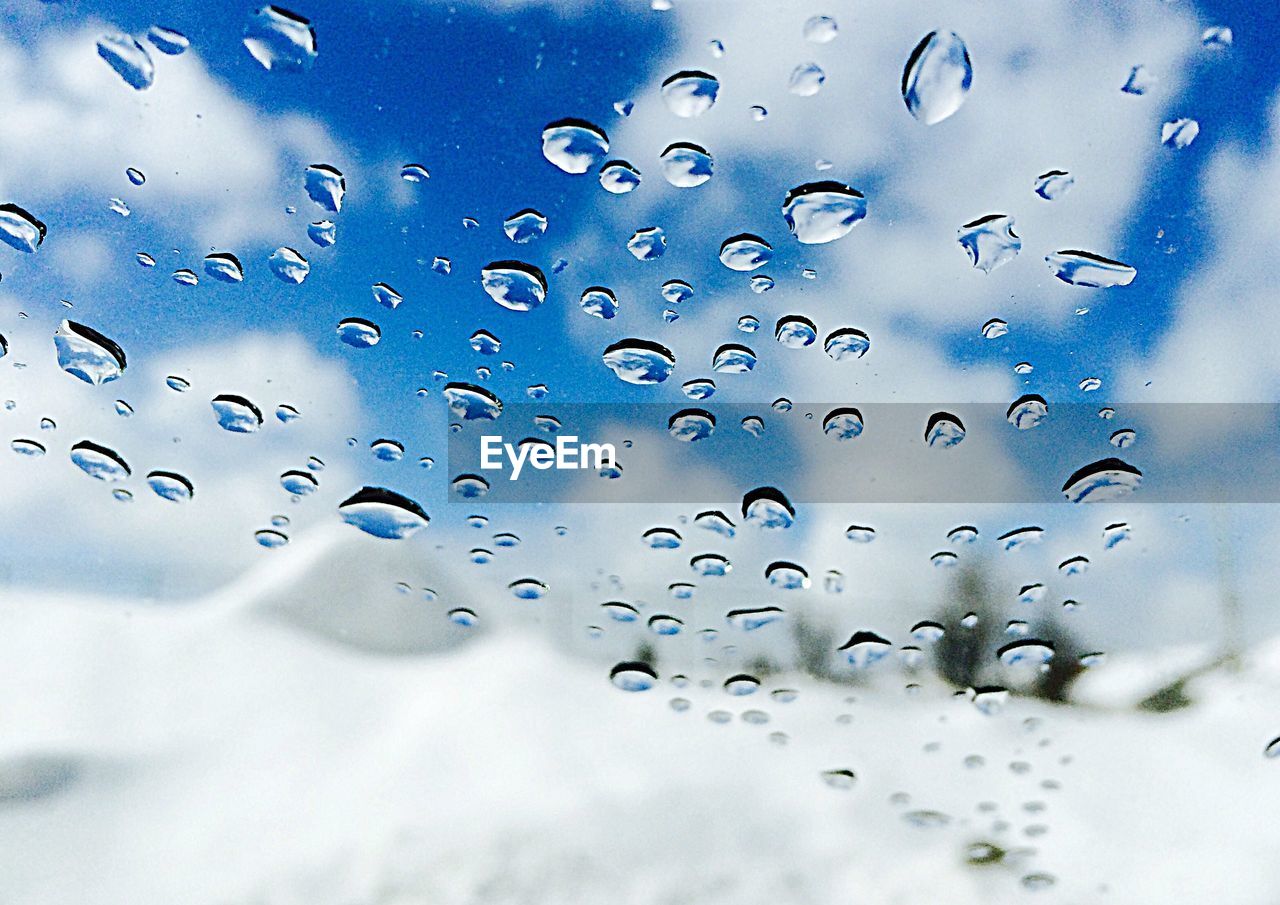 Close-up of waterdrops on glass against snowed landscape