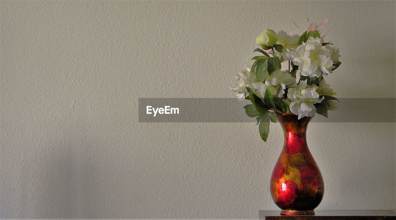 CLOSE-UP OF VASE ON TABLE AGAINST WALL