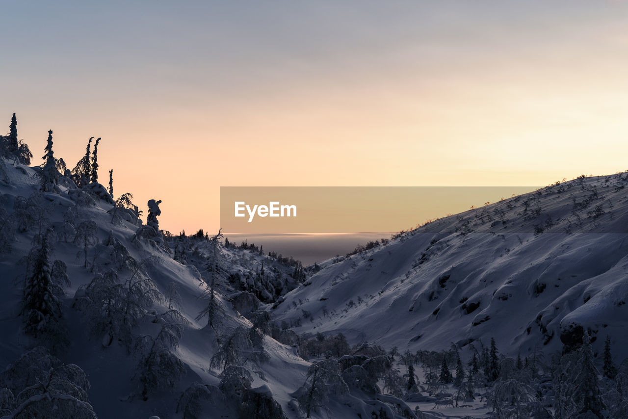 Scenic view of snow covered mountains against sky during sunset