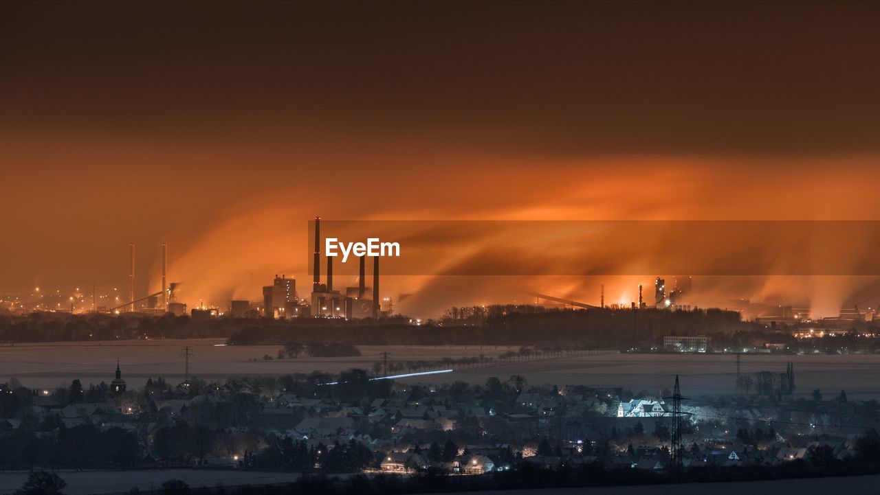 View of illuminated factory against sky