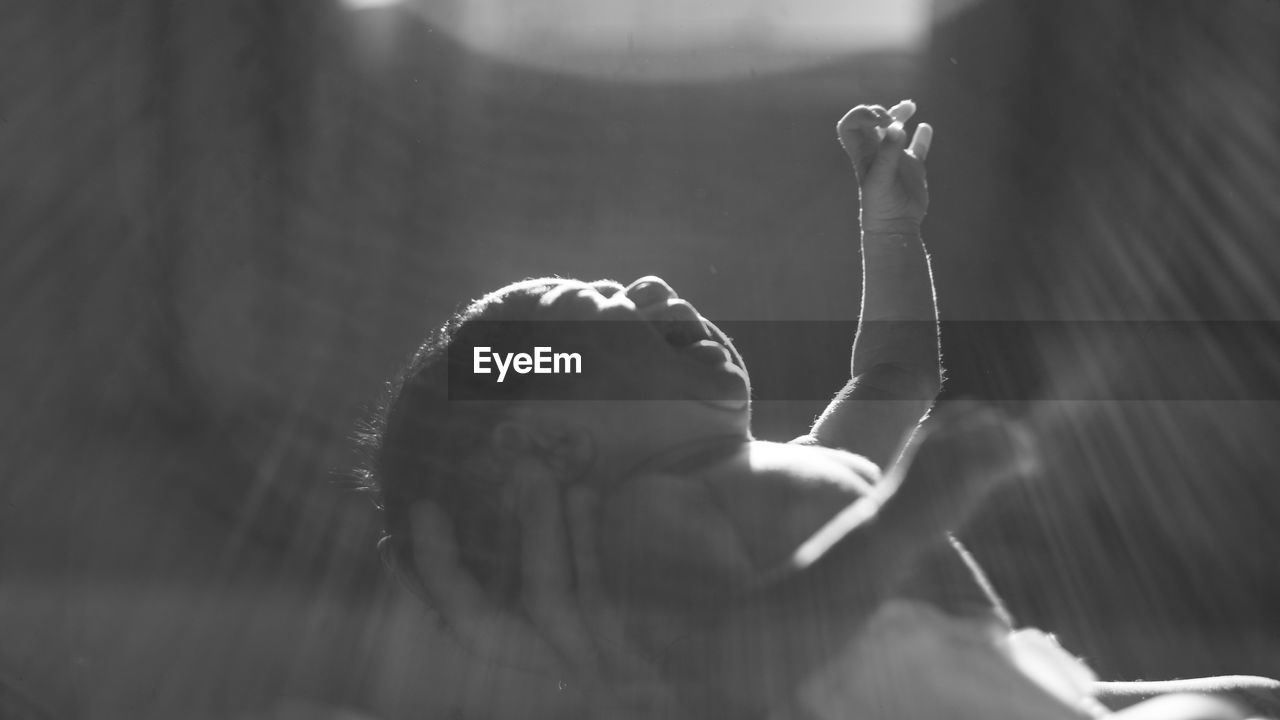 Baby boy with arms raised in darkroom