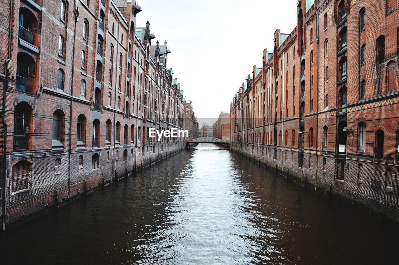 Canal amidst buildings against sky at speicherstadt