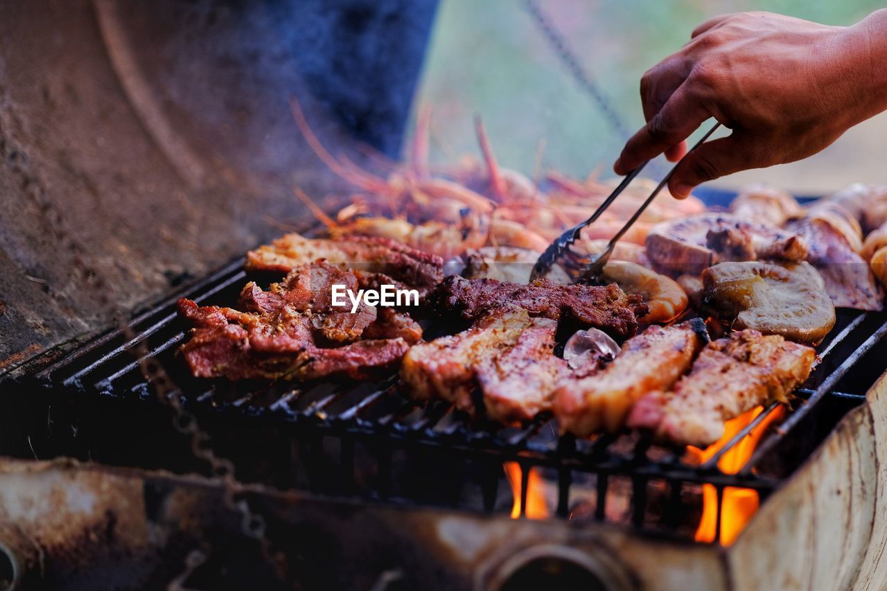 Cropped image of meat cooking on barbecue grill