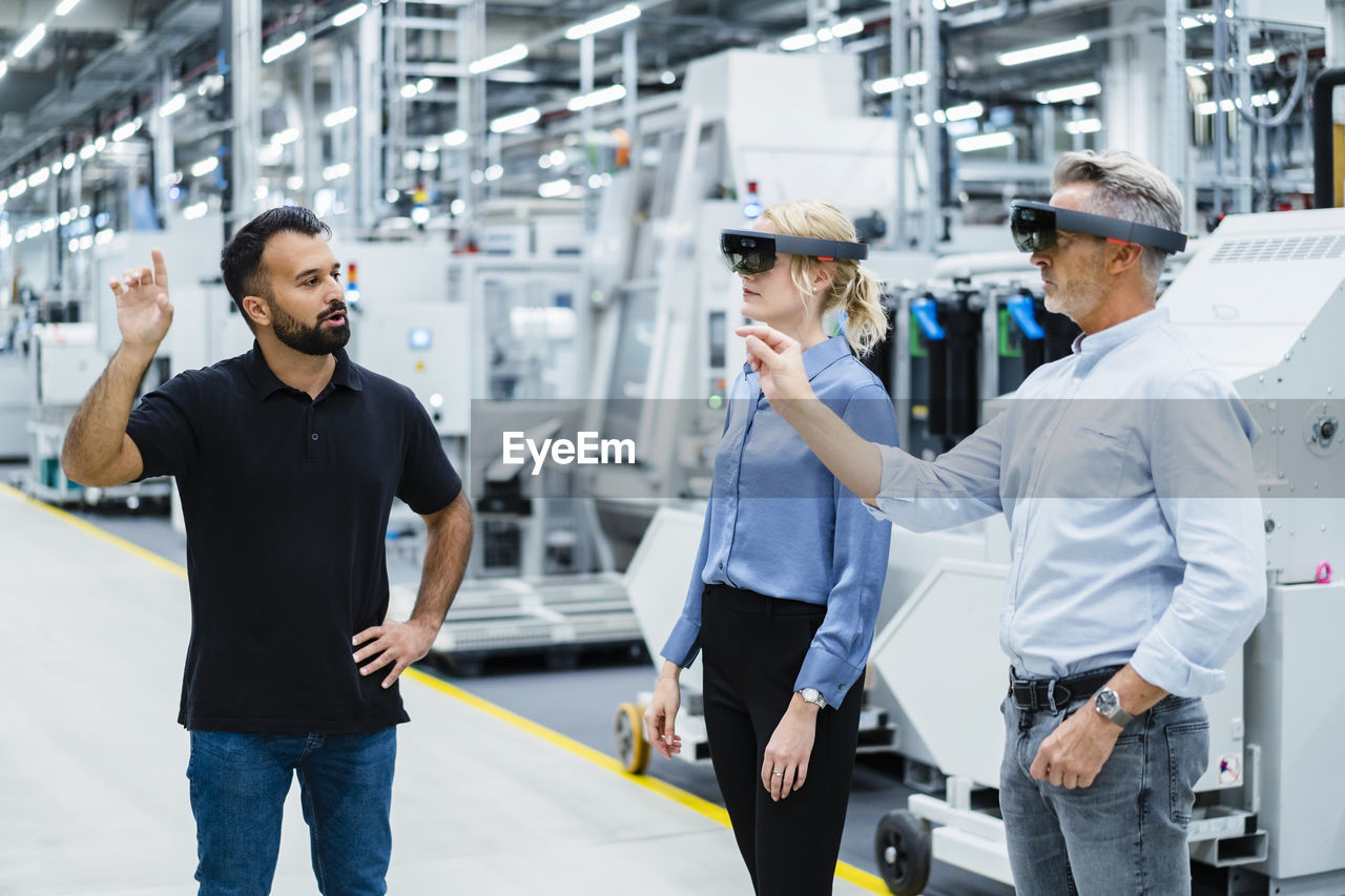 Coworkers with augmented reality glasses working at industry
