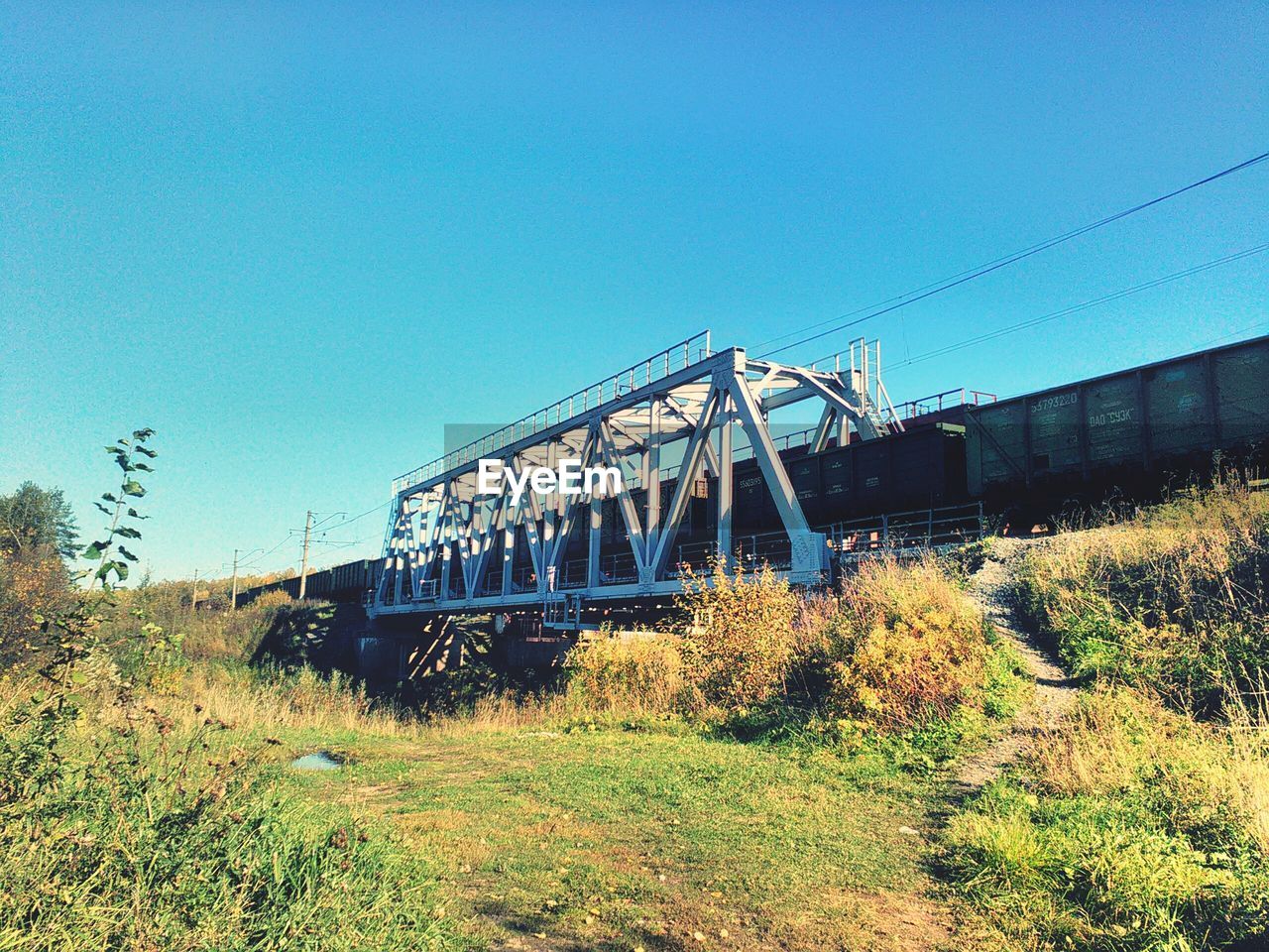 Train on bridge against clear blue sky
