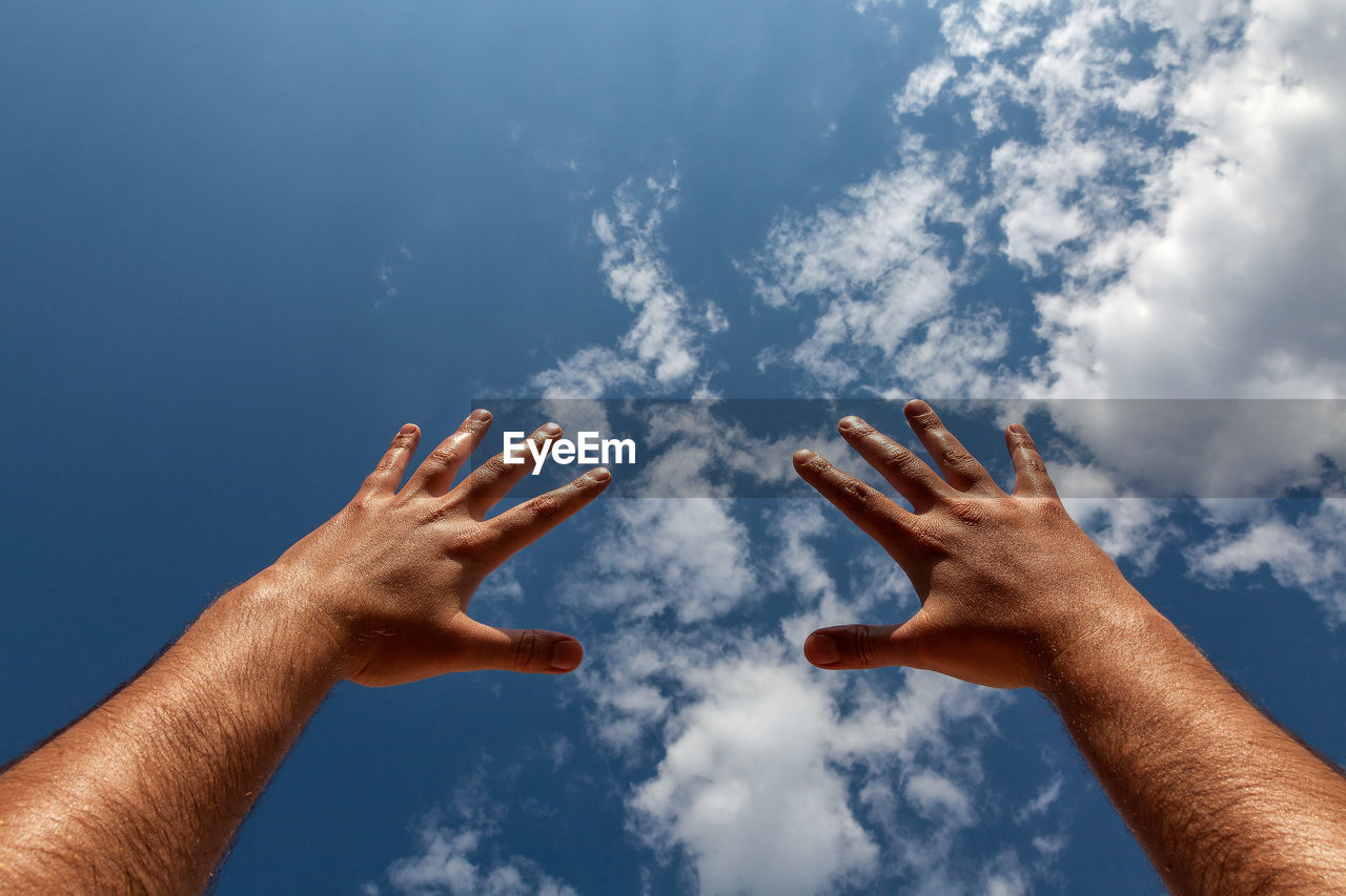 LOW ANGLE VIEW OF HANDS AGAINST SKY