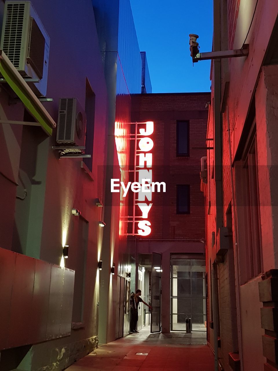 ILLUMINATED STREET AMIDST BUILDINGS IN CITY