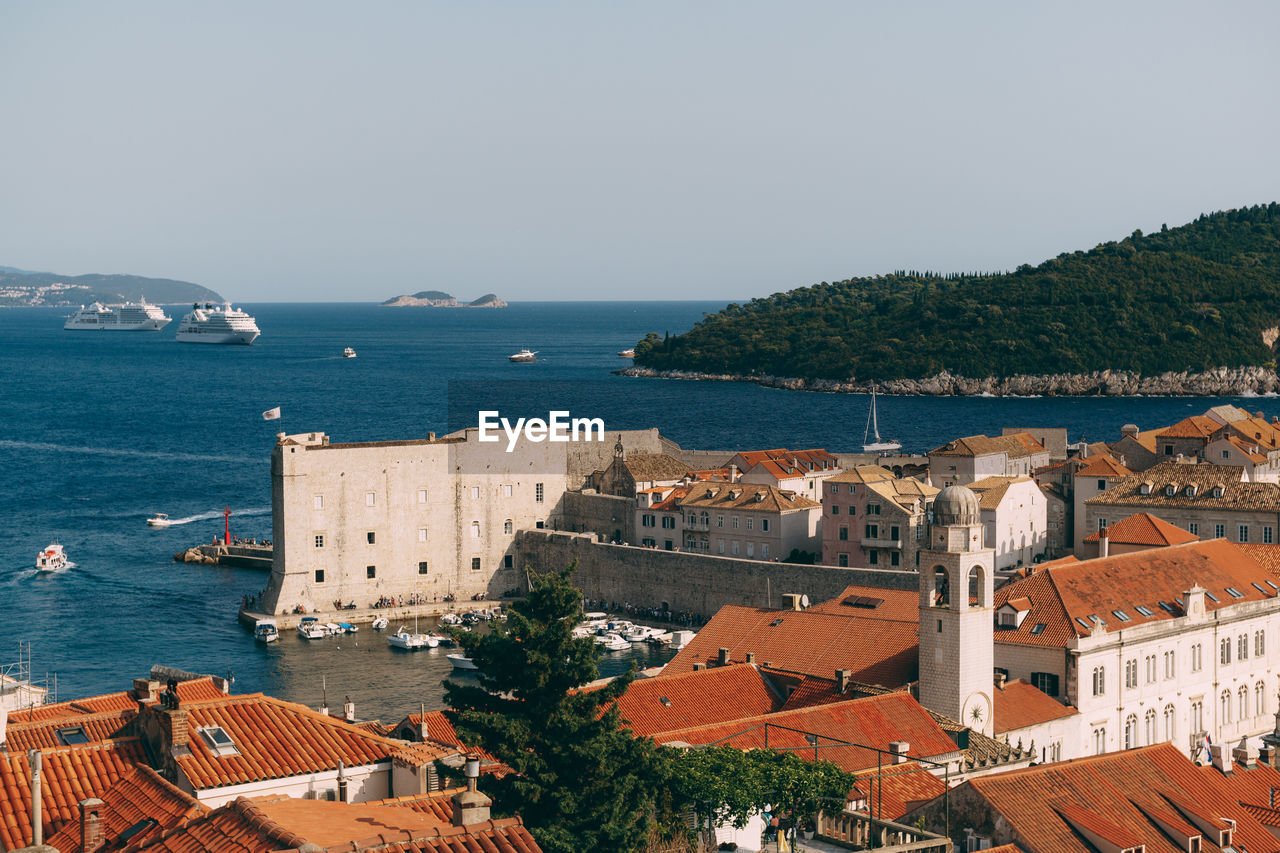 HIGH ANGLE VIEW OF BUILDINGS AND SEA AGAINST SKY