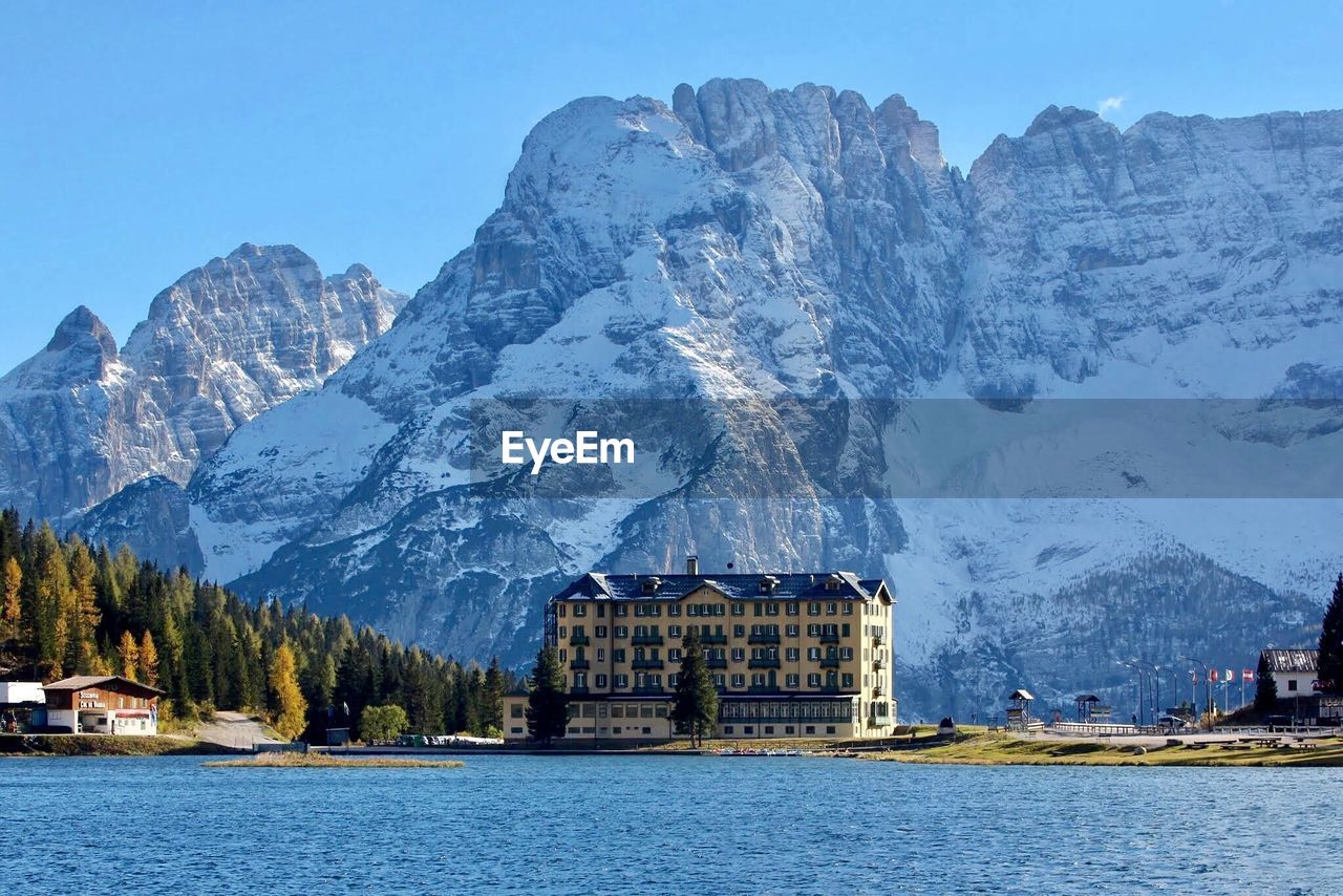 BUILT STRUCTURE BY SNOWCAPPED MOUNTAIN AGAINST SKY