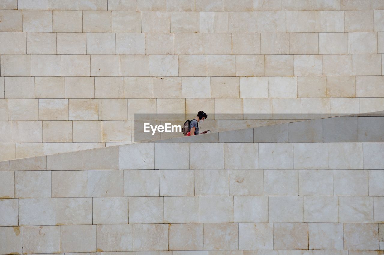 HIGH ANGLE VIEW OF WOMAN WALKING BY WALL