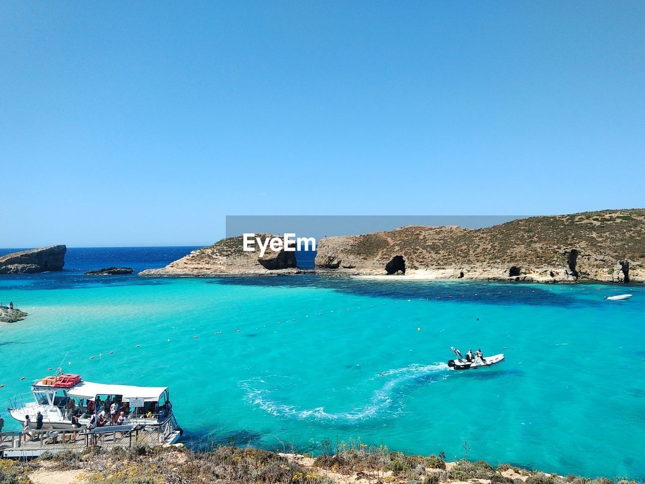 People riding boats in sea against clear sky