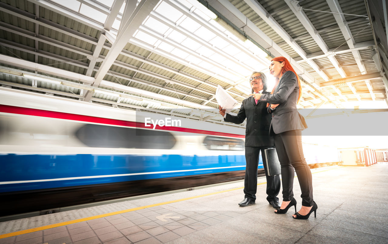 Full length of business people standing on railroad station platform