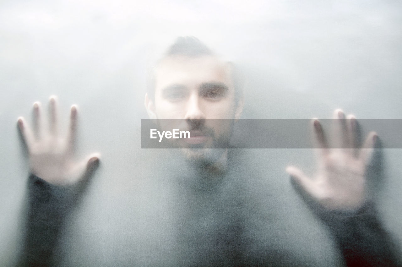 Portrait of man looking through condensed glass