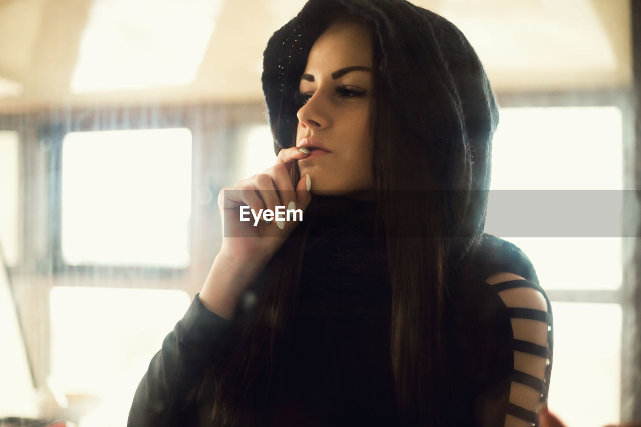 Thoughtful young woman wearing hooded shirt at home