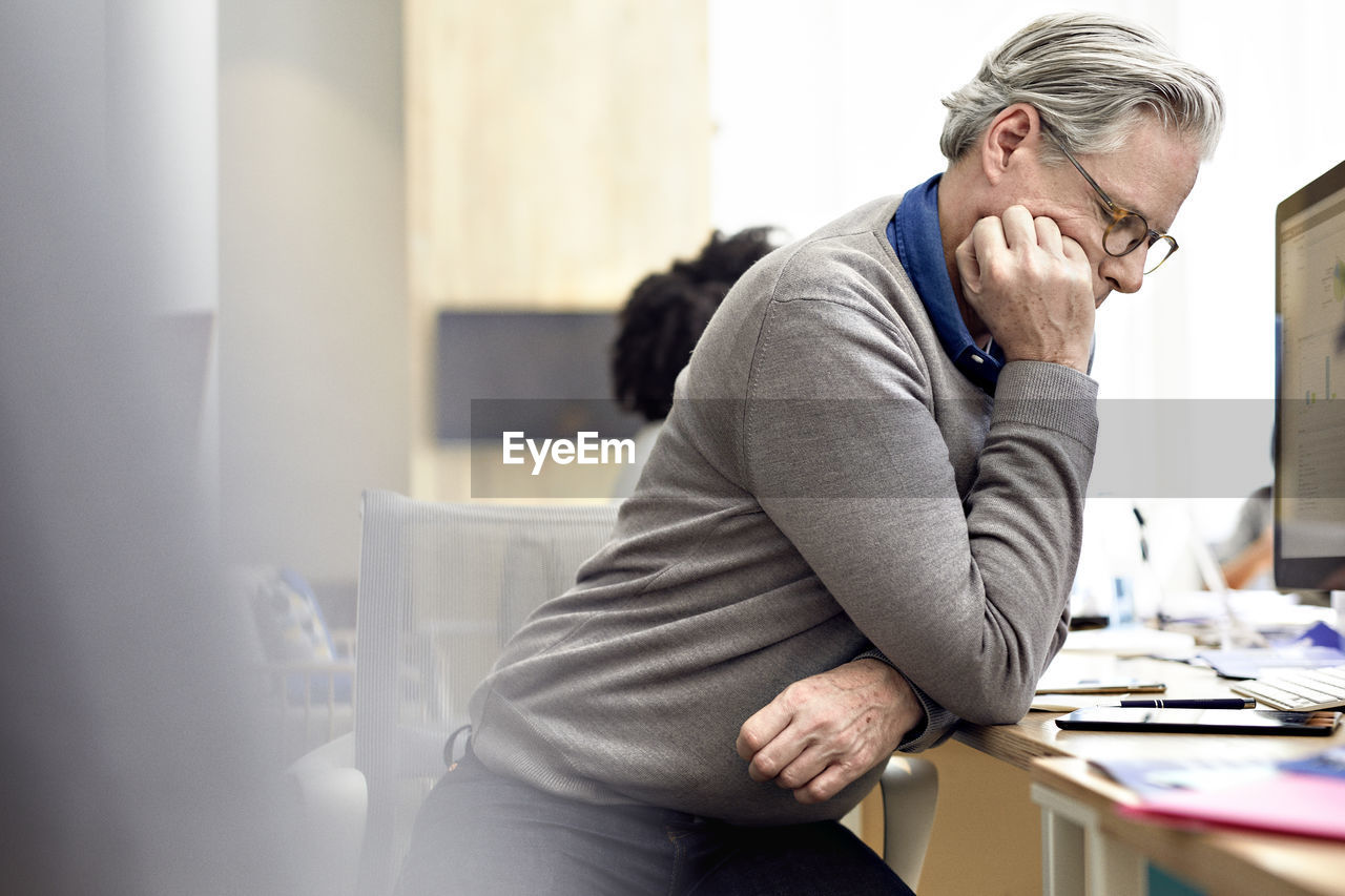 Businessman looking at smart phone with female colleague sitting in background