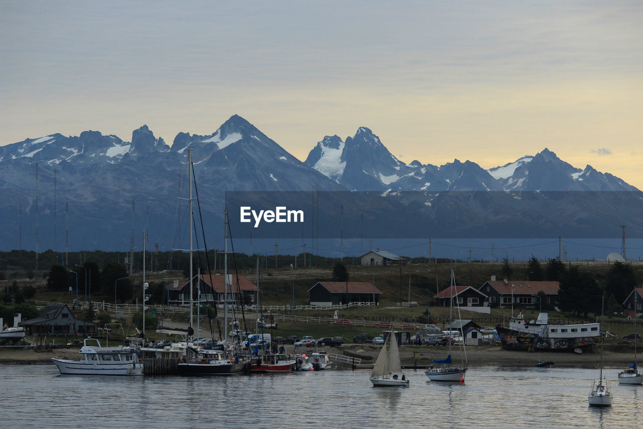 SAILBOATS MOORED BY BUILDINGS AGAINST SKY DURING WINTER