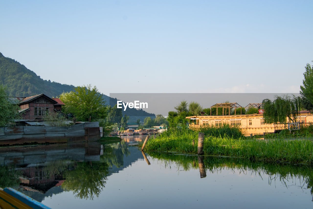 Houses by lake against clear sky