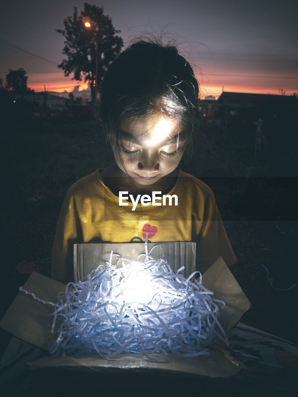 Close-up of girl holding illuminated box at night