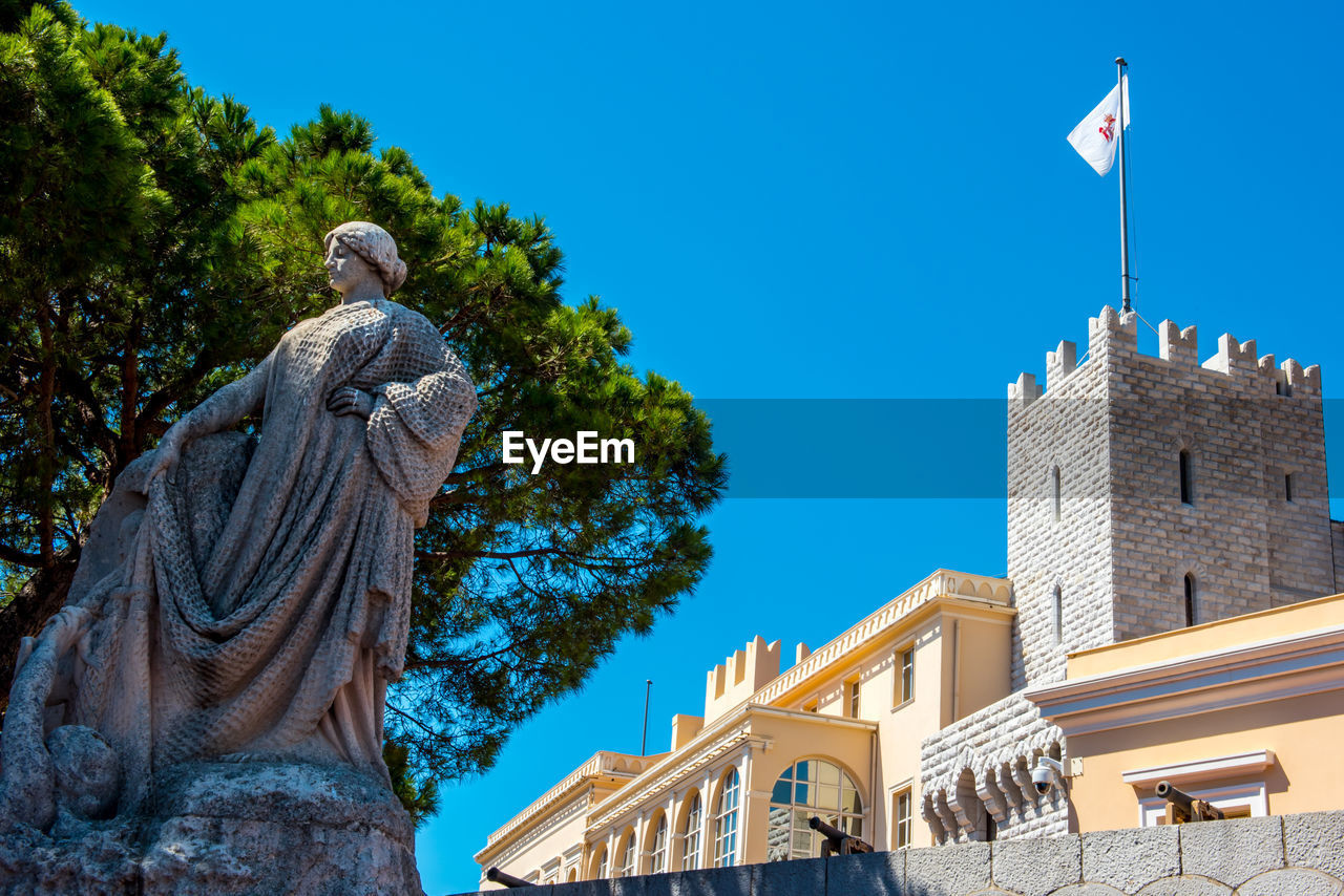 Low angle view of statue and palace against blue sky