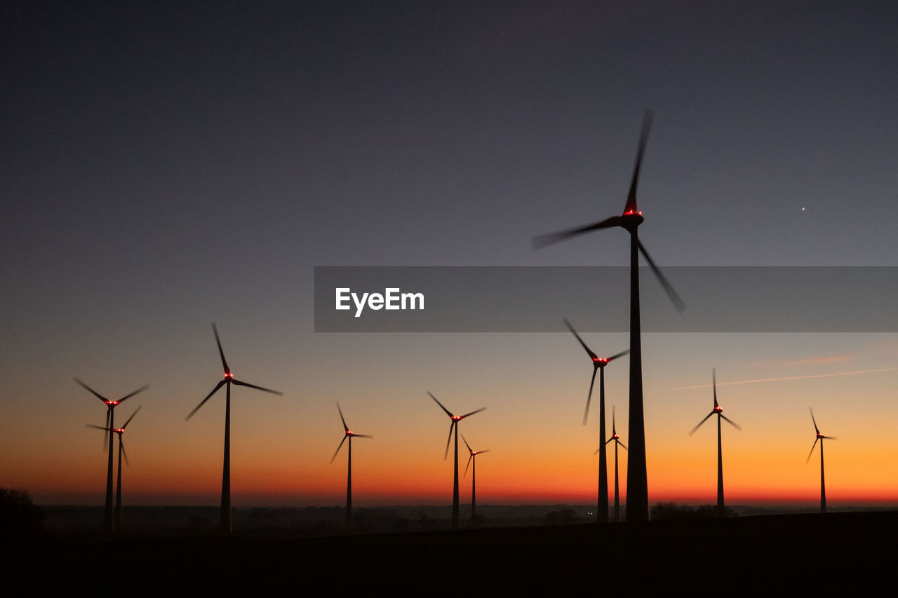 low angle view of silhouette windmills against clear sky during sunset