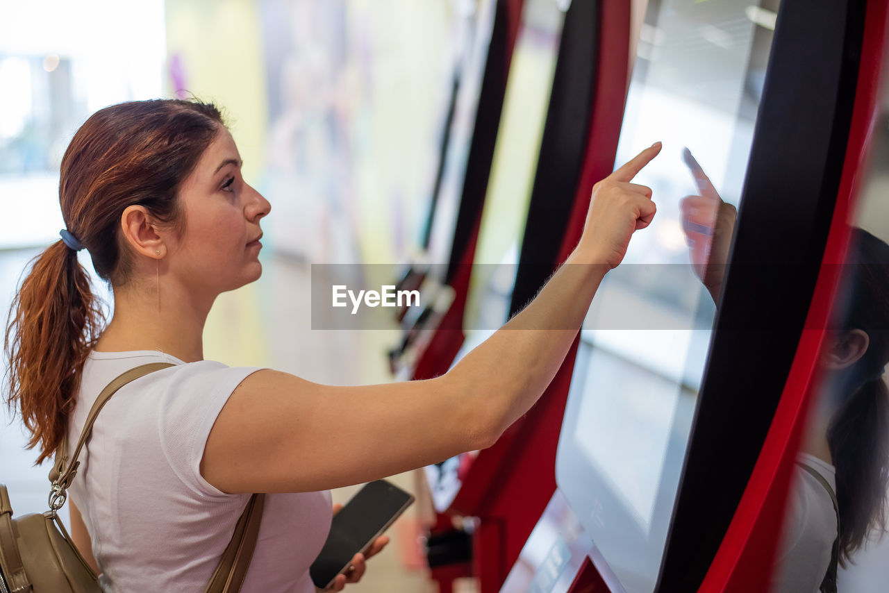 Side view of woman using atm machine