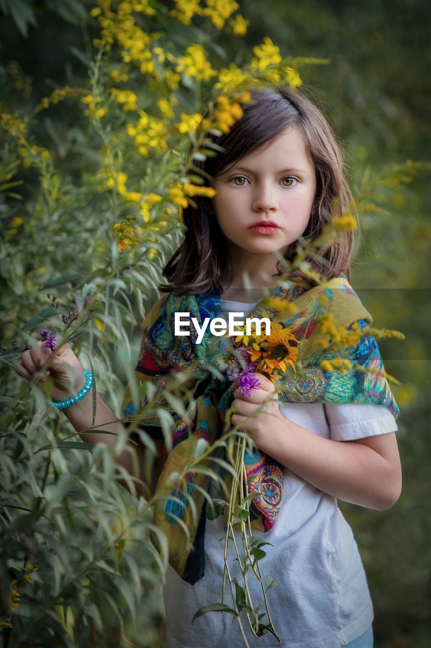 portrait of smiling young woman standing by plants