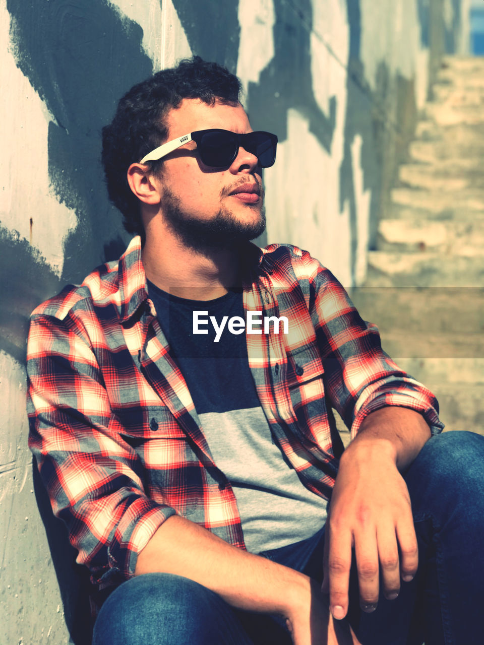 Young man wearing sunglasses sitting outdoors
