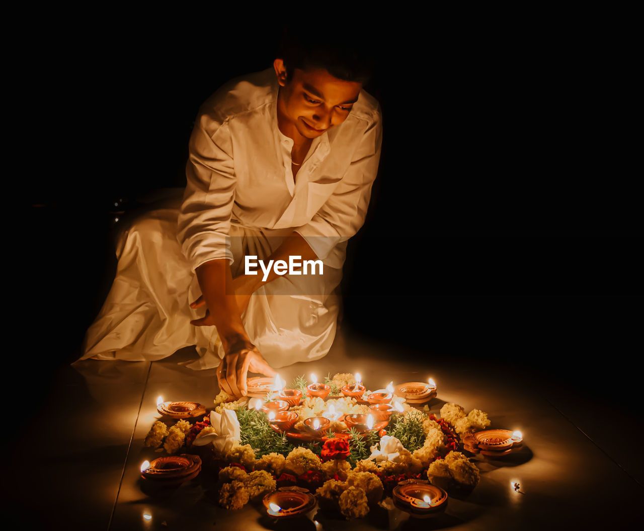 Man standing by illuminated candles on table