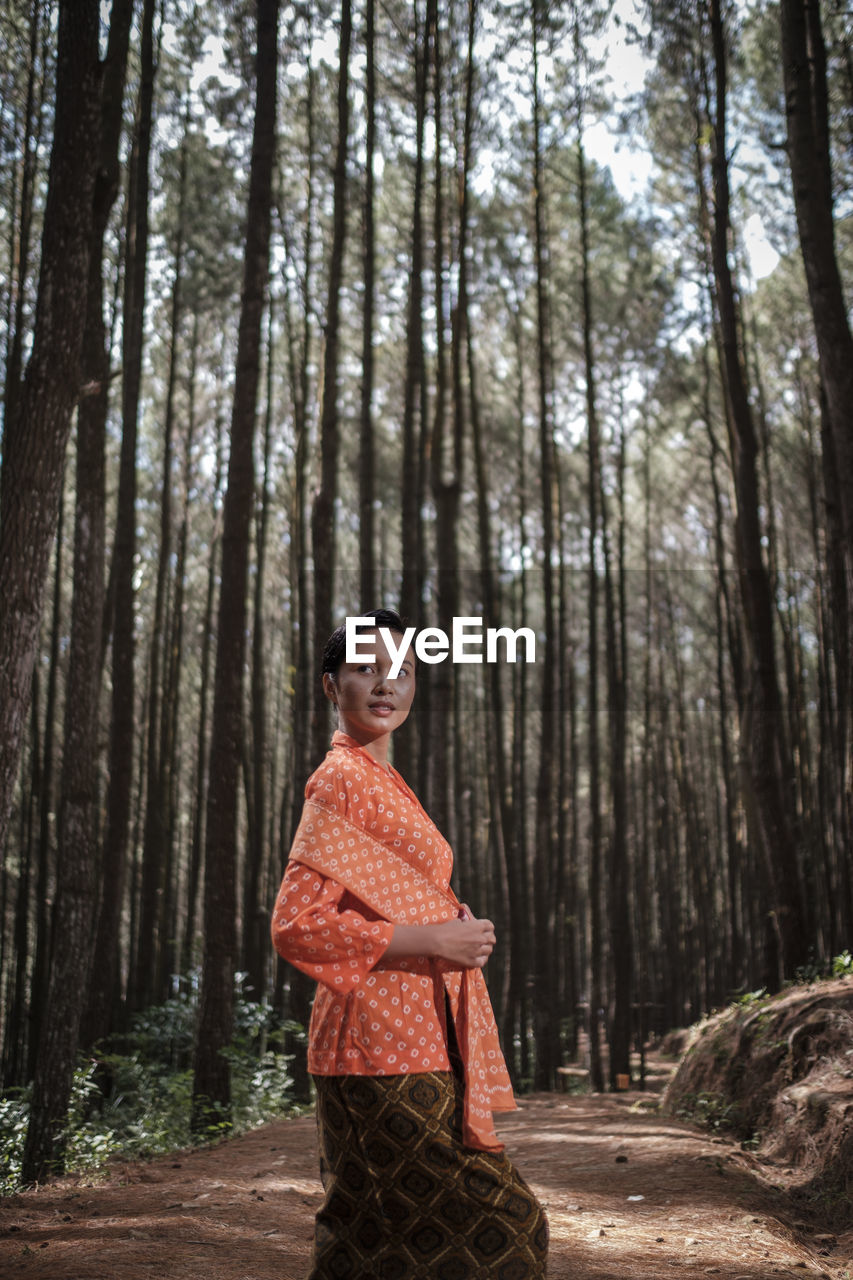 Woman standing against trees in forest