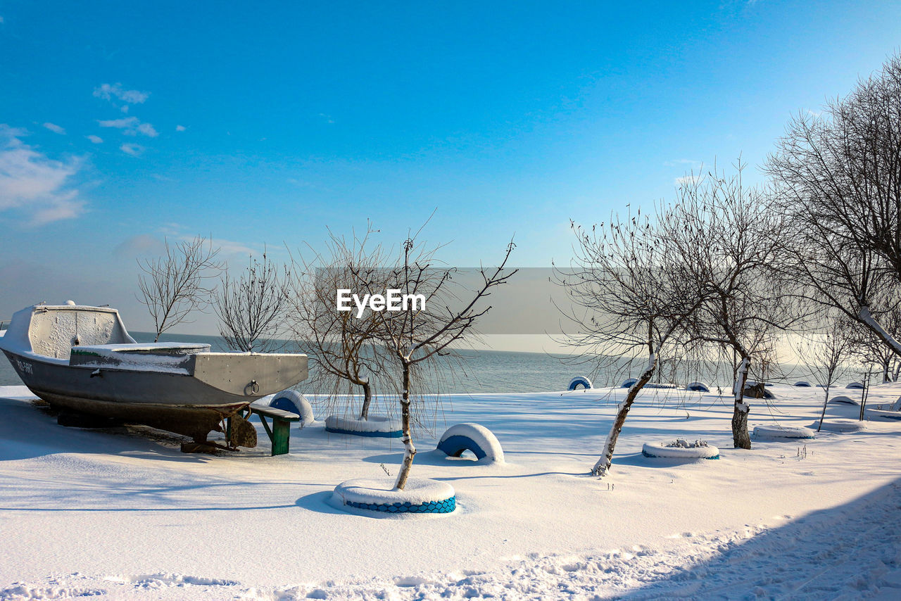 SNOW COVERED FIELD AGAINST BLUE SKY