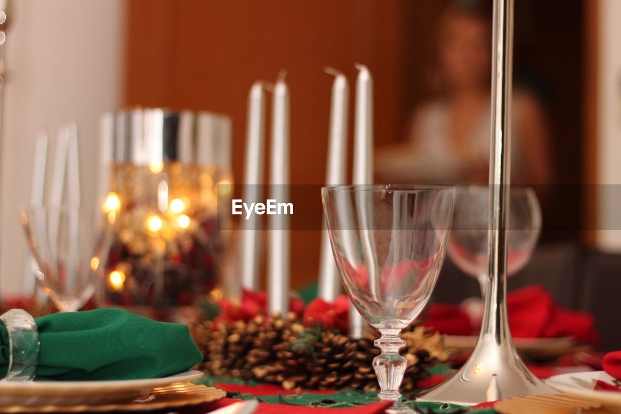 Close-up of wineglasses with candles and pine cones on dining table during christmas