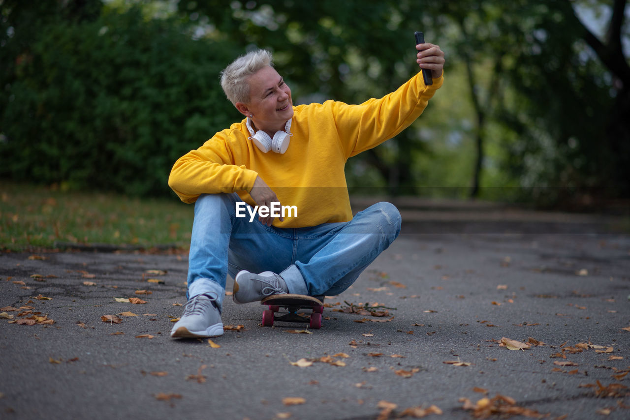 autumn, yellow, one person, adult, men, footwear, person, full length, lifestyles, emotion, child, casual clothing, leisure activity, clothing, limb, senior adult, tree, sports, sitting, activity, jeans, seniors, relaxation, plant part, outdoors, leaf, nature, park, human face, park - man made space, gray hair, fun, human limb, happiness