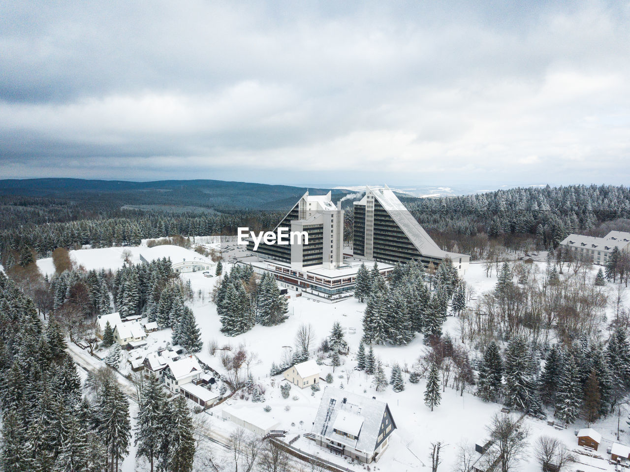 AERIAL VIEW OF SNOW COVERED LANDSCAPE AGAINST CLOUDY SKY