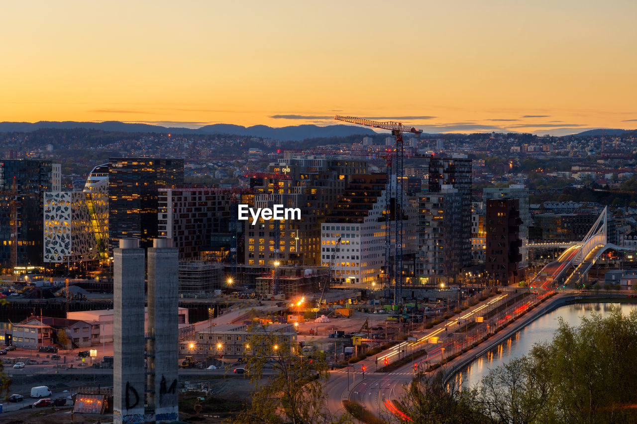 High angle view of illuminated cityscape against sky at sunset